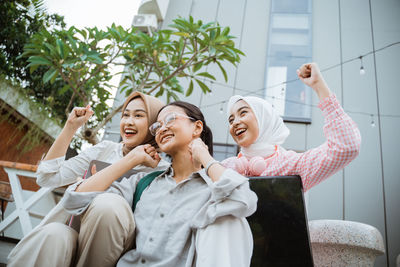 Portrait of smiling friends standing against wall