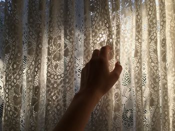 Close-up of human hand against curtain