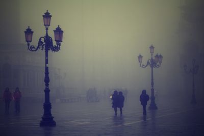People on illuminated street light in city