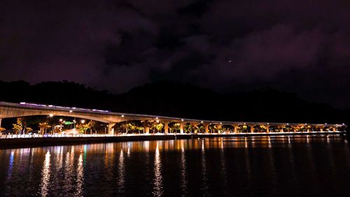Illuminated bridge over river against sky at night