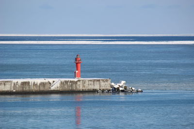 Lighthouse by sea against sky