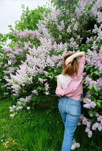 Woman standing by pink flowering plants