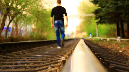 Rear view of woman walking on railroad tracks