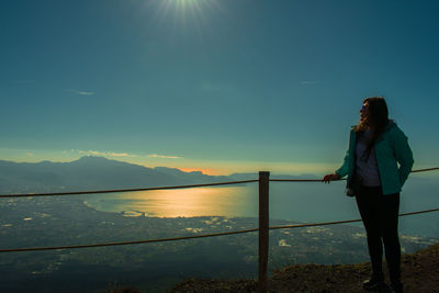 Mid adult woman standing on observation point against blue sky during sunset