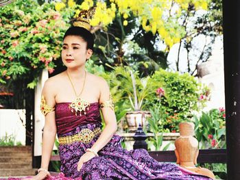 Beautiful woman in traditional dress sitting in park