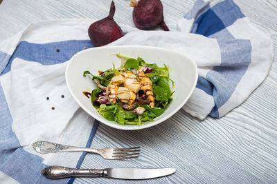 Deep bowl of arugula salad with cheese and chicken fillet slices. dressed with balsamic sauce.