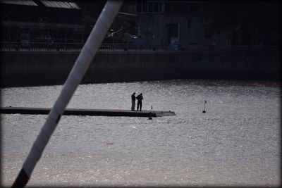 Silhouette people standing on riverbank