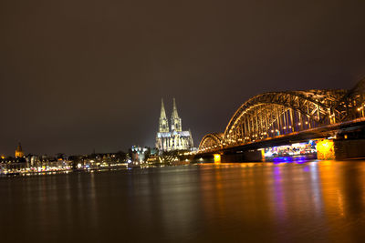 Illuminated bridge over river at night