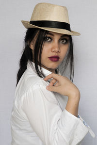 Portrait of young woman wearing hat against white background