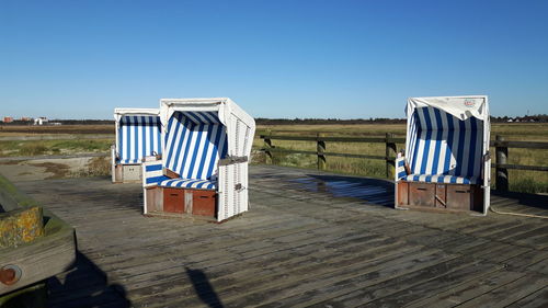 Empty chairs on beach against clear blue sky