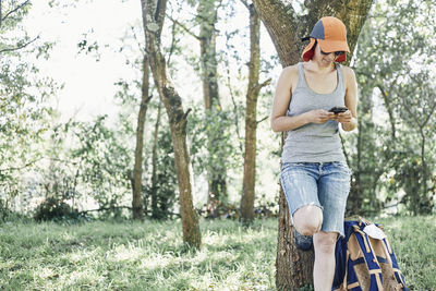 Full length of senior woman using phone while standing on land