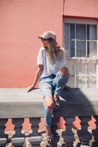 Full length of young woman standing against brick wall