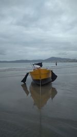 Boat moored on beach against sky