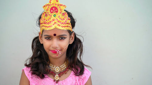 Portrait of beautiful young woman standing against wall