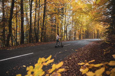 Female riding the electric scooter in the autumn park,modern transportration lifestyle concept	