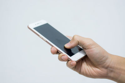 Close-up of hand using mobile phone against white background
