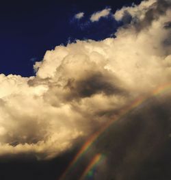 Low angle view of rainbow against cloudy sky