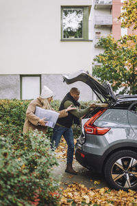 Mature woman assisting man while loading car trunk during relocation of house