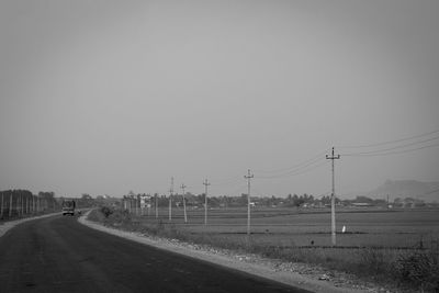 Road by field against clear sky
