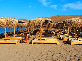 Lounge chairs and parasols on beach against sky