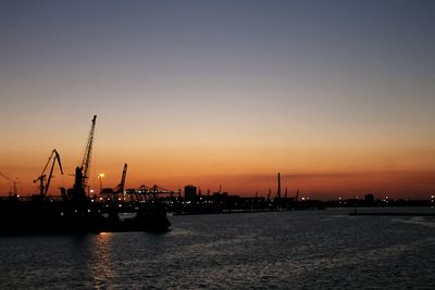 Silhouette cranes at port of odessa against clear sky during sunset