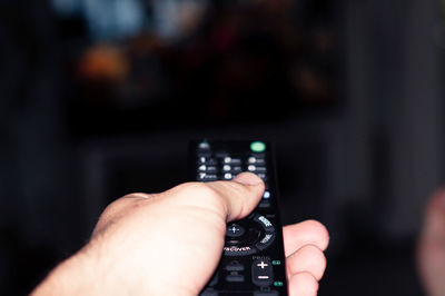 Cropped image of man holding remote control at home