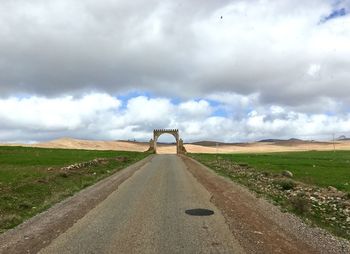 Road amidst field against sky