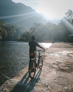 Rear view of man riding bicycle on water