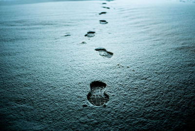 High angle view of footprints on wet shore