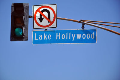 Low angle view of road sign against clear blue sky