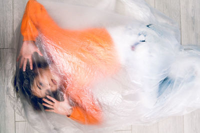 Portrait of teenage girl wrapped in plastic on floor