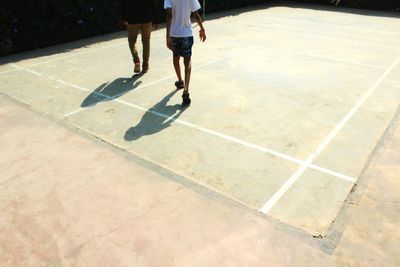 Low section of men walking on court during sunny day