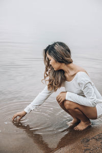 Side view of woman sitting on beach