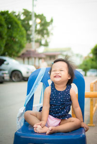 Girl smiling while sitting on chair at road