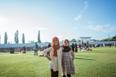 Portrait of smiling couple standing on field against sky