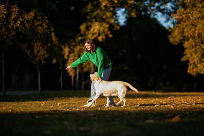 Young woman and her obedient big dog in autumn park