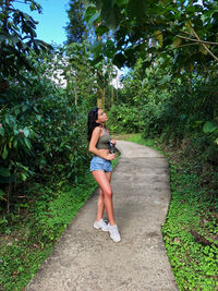 Side view of woman standing on footpath amidst plants