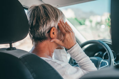 Senior woman having headache in car