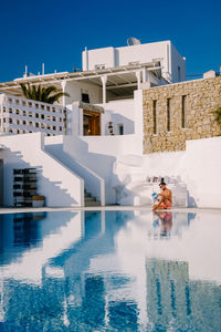 People by swimming pool against building