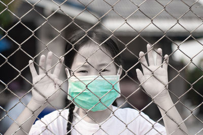 Close-up portrait of a girl seen through chainlink fence