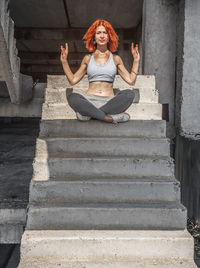 Cheerful woman, relaxing after fitness workout in park, sitting on concrete steps outdoors