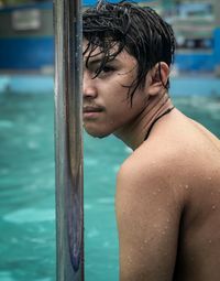 Portrait of shirtless man by swimming pool