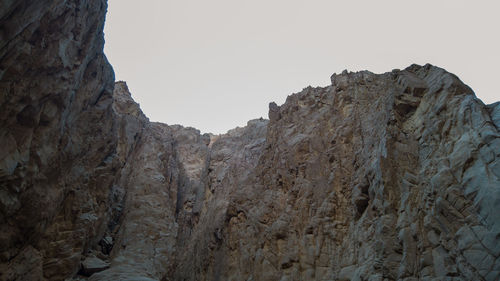 Low angle view of rocky mountains against clear sky