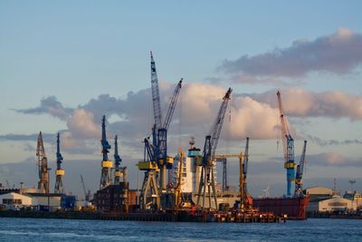 Cranes at commercial dock against sky