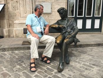 Full length of man sitting on wall