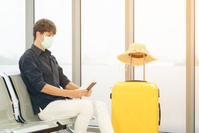 Young man using mobile phone while sitting on chair