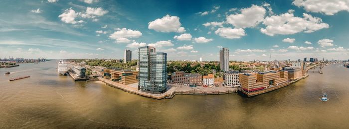 Panoramic view of bay and buildings against sky