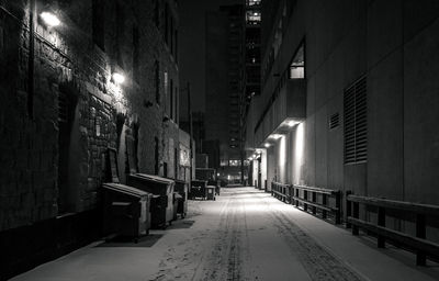 Empty alley amidst buildings in city at night