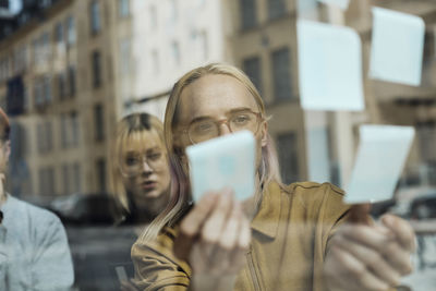 Non-binary computer programmer brainstorming with female colleague at tech start-up office