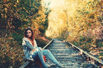 Portrait of young woman sitting on railroad track